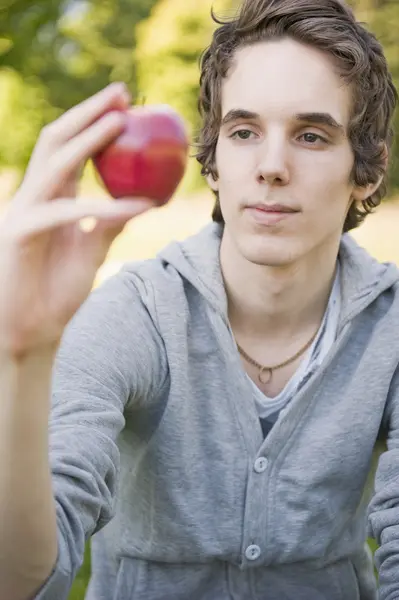 Młody człowiek trzyma jabłko — Zdjęcie stockowe