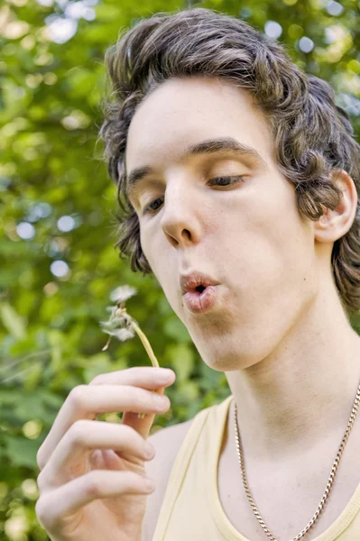 stock image Young man blowing on a dandelion