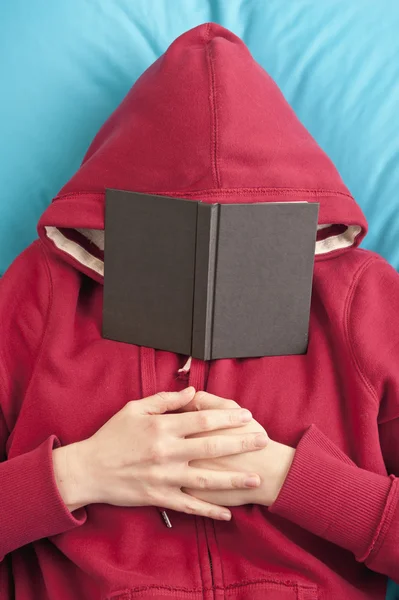 stock image Lying down with book covering face