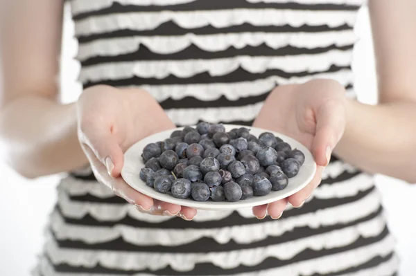Young woman holding a plate with blueberries — Stock Photo, Image