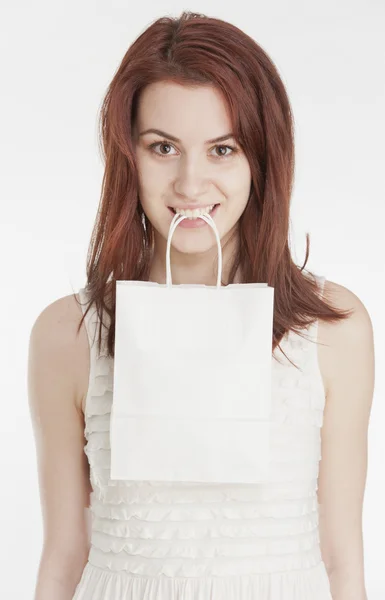 Mujer joven sosteniendo una bolsa de compras blanca en su boca — Foto de Stock