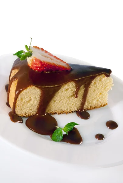 Ein Stück Biskuitteig mit Schokoladensauce auf einem weißen Teller. — Stockfoto