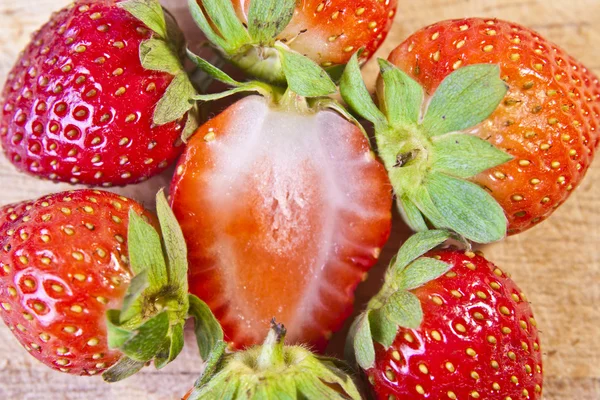 Eine Gruppe ganzer Bio-Erdbeeren um eine aufgeschnittene Erdbeere — Stockfoto