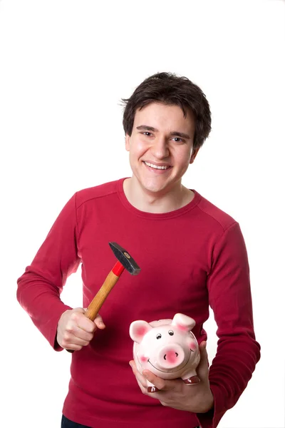Junger Mann zerbricht sein Sparschwein lizenzfreie Stockfotos