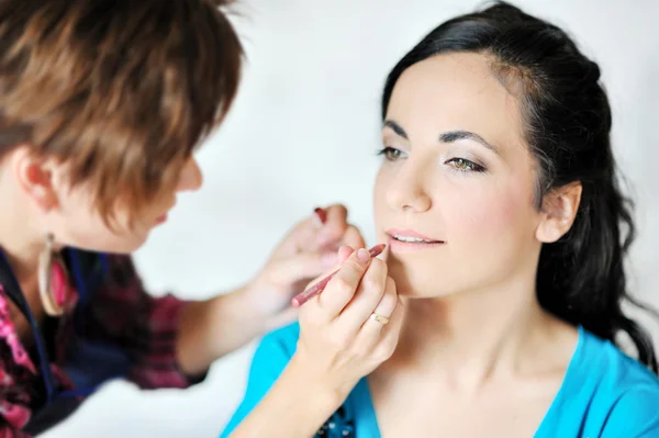 Young beautiful bride applying wedding make-up by make-up artist — Stock Photo, Image
