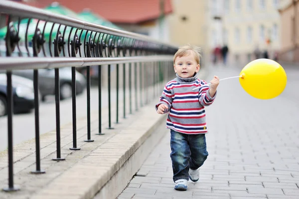 Menino adorável com balão amarelo em heand — Fotografia de Stock