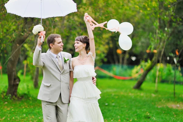 Happy bride and groom walking together in a park — Stock Photo, Image