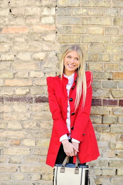 Portret van een glimlachende vrouw in het rood tegen de achtergrond van de muur — Stockfoto