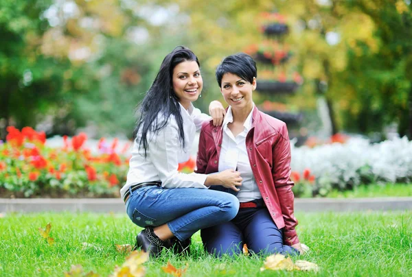 Madre feliz con su hija sentada en una hierba al aire libre —  Fotos de Stock