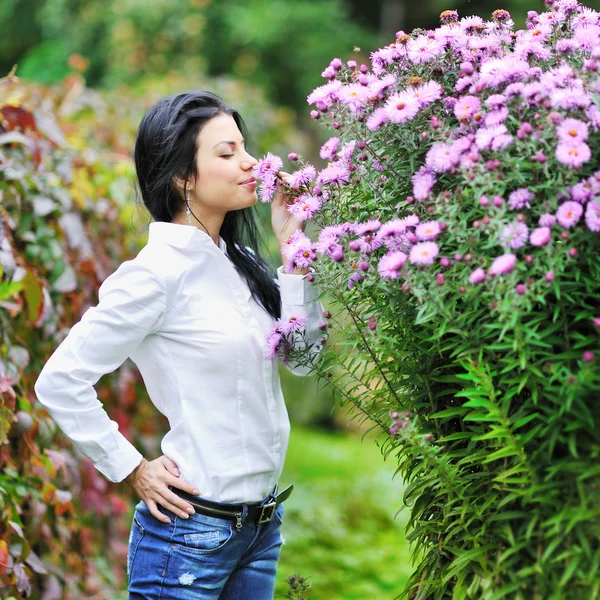 Mooie volgens vrouw ruikende bloemen in een tuin — Stockfoto