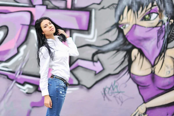 Bella ragazza in posa contro muro grafitti — Foto Stock