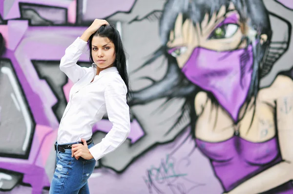 Mooi meisje poseren tegen graffiti muur — Stockfoto
