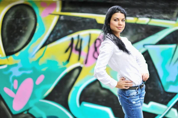 Schönes Mädchen posiert gegen Grafitti-Wand — Stockfoto