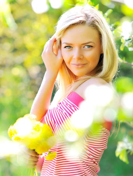 Vacker kvinna med blommor i en park — Stockfoto