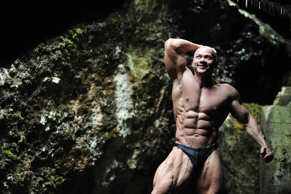Jonge bodybuilder in een grot — Stockfoto