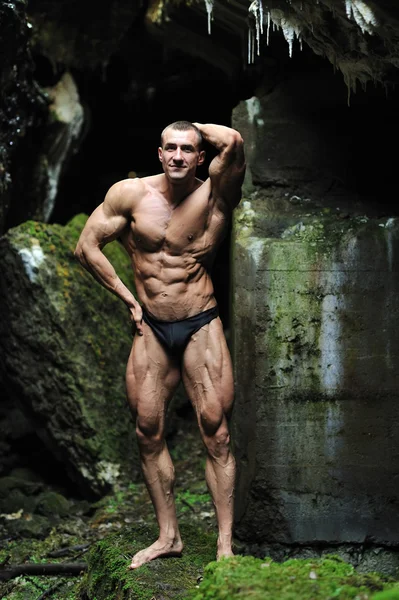 Fitness man poserar i en grotta — Stockfoto