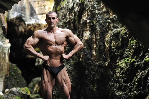 Bodybuilder in a cave — Stock Photo, Image