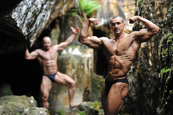 Bodybuilder posing behind another bodybuilder in the blurring — Stock Photo, Image