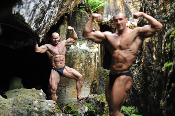 Bodybuilder poserar efter en annan bodybuilder i den oskärpa — Stockfoto
