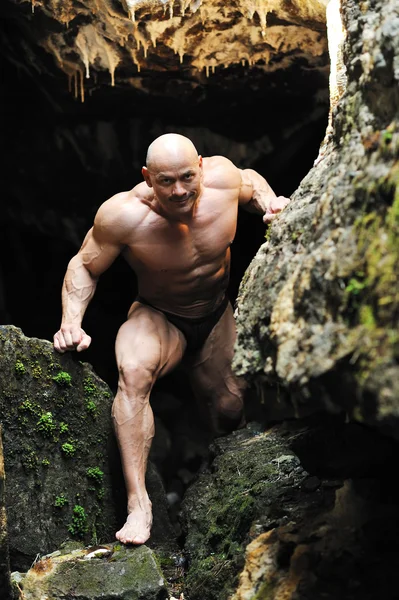 Muscular man climbs out of the cave — Stock Photo, Image