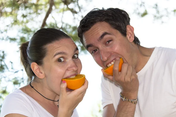 Pareja joven comiendo naranja fresca — Foto de Stock