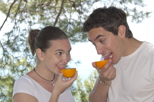 Ungt par som slikker fersk oransje – stockfoto