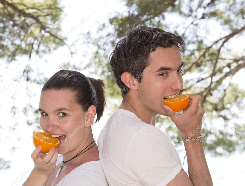 Young couple eating fresh orange