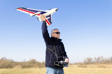 Happy senior RC modeller launching RC plane clipart