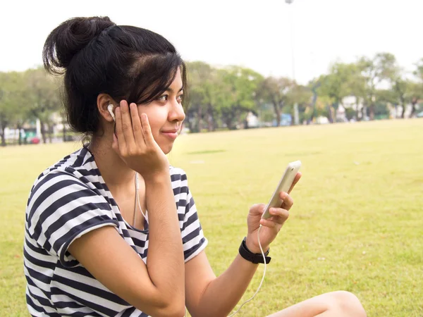 Een jong meisje met koptelefoon buitenshuis. luisteren muziek — Stockfoto