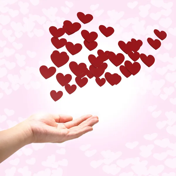 Muitos corações vermelhos na mão, fundo rosa — Fotografia de Stock
