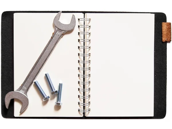 Schraubenschlüssel und Muttern am Notizbuch. — Stockfoto