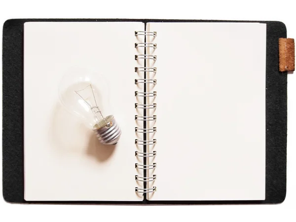 Glühbirne auf Notizbuch gelegt — Stockfoto
