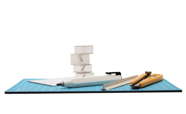 Cortador, lápiz, escala y modelo arquitectónico colocado en cutti azul — Foto de Stock
