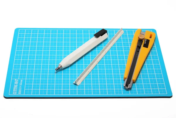 Κόπτης, μολύβι και κλίμακας τοποθετούνται σε μπλε κοπής χαλί. — Φωτογραφία Αρχείου