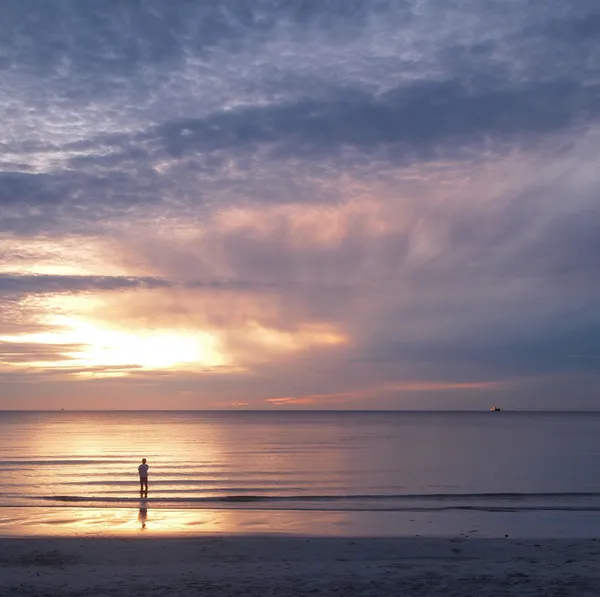 Νεαρός άνδρας και το ηλιοβασίλεμα στη θάλασσα — Φωτογραφία Αρχείου