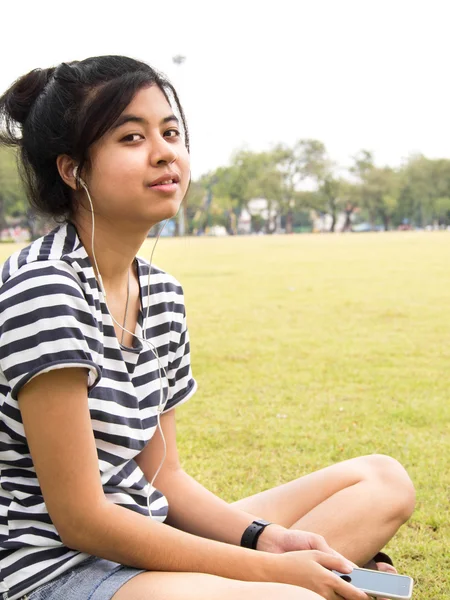 Uma jovem com auscultadores ao ar livre. Ouvir música — Fotografia de Stock