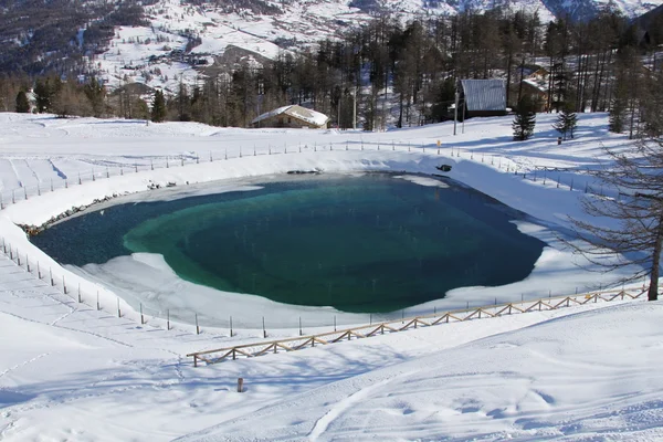 Искусственное озеро в горах рядом с деревней — стоковое фото