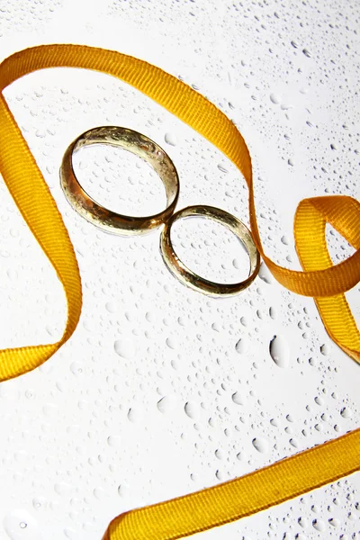 Wedding rings with drops and orange ribbon — Stock Photo, Image