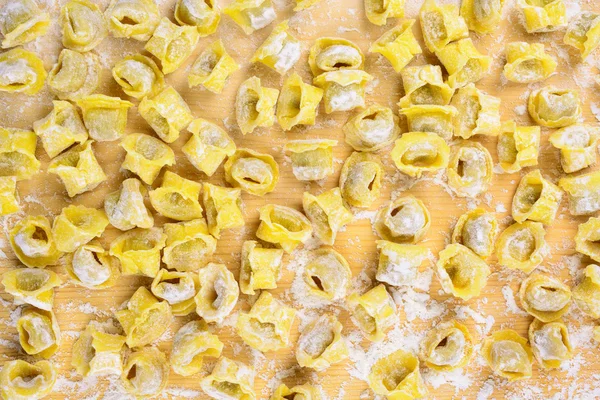Tortellini pasta italiana rellenos de carne con harina en respaldo de madera — Foto de Stock