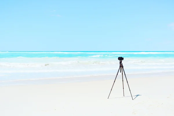 Digitální fotoaparát a stativ na bílé pláži pro krajinu fotografic — Stock fotografie