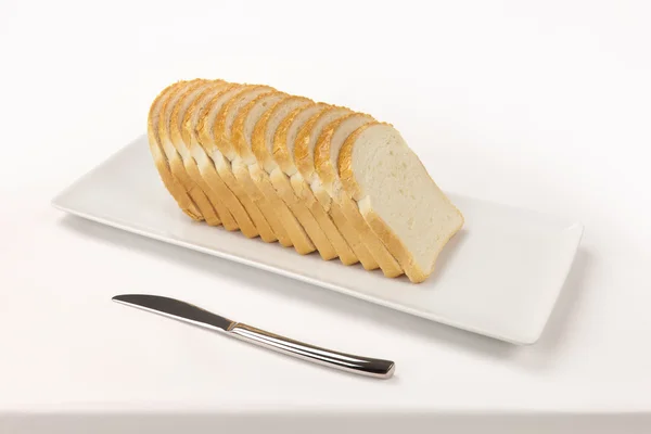 Sliced ​​bread on rectangular dish and a knife — Stock Photo, Image