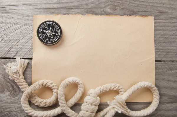 Oude kompas, touw en een oud papier op houten achtergrond — Stockfoto