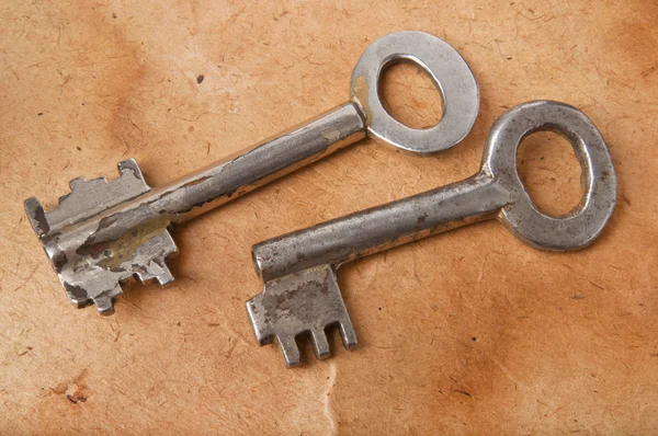 stock image The old keys on the background of the old paper