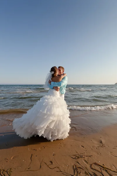 Bruid en bruidegom kussen op het strand — Stockfoto