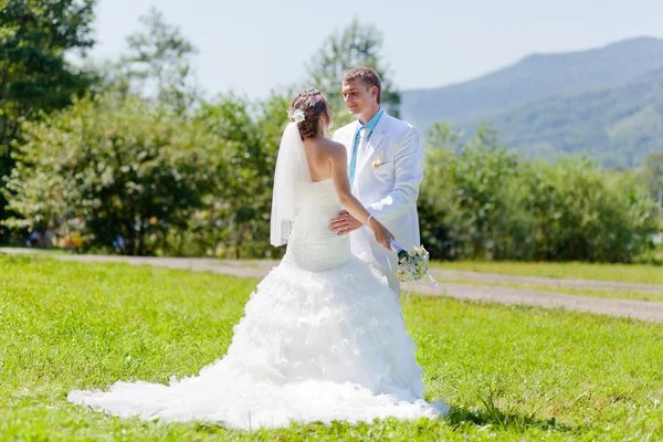 Bride and groom hugging at green grass — Stock Photo, Image