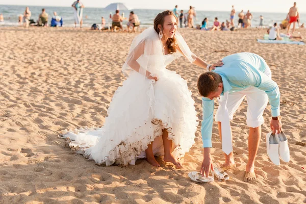 Nevěsta a ženich na přeplněné pláži — Stock fotografie