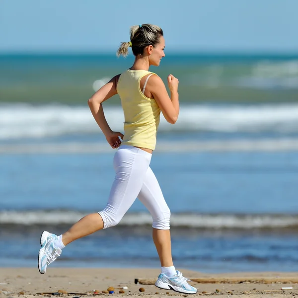 Genç bir kadın sahilde koşuyor. — Stok fotoğraf