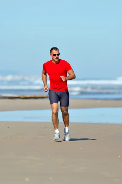 Young man jogging on the beach in summer — Stock Photo, Image