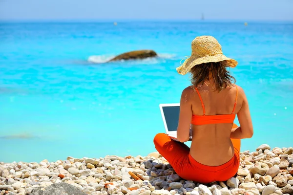 Молода жінка використовує ноутбук на пляжі — стокове фото