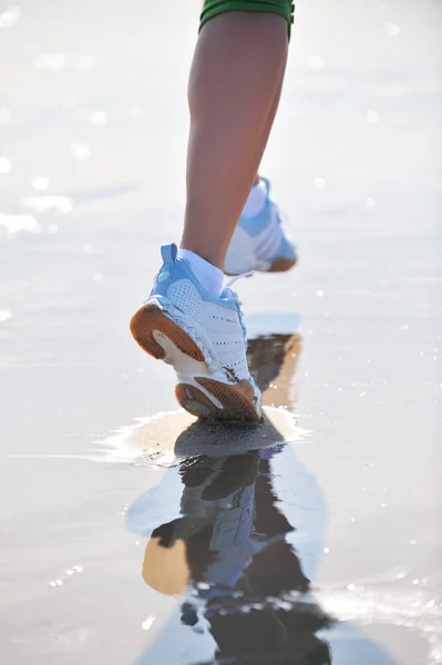 Voeten van jonge vrouw joggen op het strand — Stockfoto